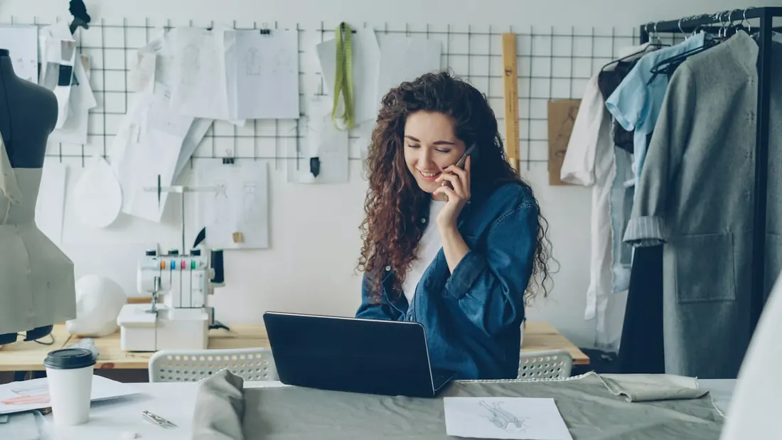Small business owner taking a customer call at her laptop in her studio